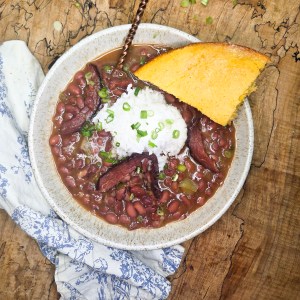 Red Beans and Rice is a slow cooked classic made with leftover ham bone, the holy trinity and signature spices served over white rice.