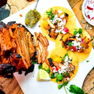 Cantina style Tacos al Pastor are marinated, grilled on the rotisserie and shaved off into your corn tortilla with bits of charred pineapple.