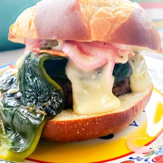 Ahhh, the sexy Poblano Burger. The perfect addition to your Memorial Day BBQ. Inspired by flavors of the Southwest, this burger is topped in a luscious green chile queso layered with thick cut smokey bacon, fire roasted poblano peppers and pickled red onions.