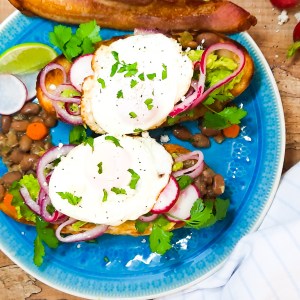 Avocado Breakfast Molette is a Mexican inspired avocado toast with layers of pinto beans, smashed avocado, pickled onions, Cotija cheese, cilantro and a fried egg on a bolillo roll.