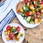 Panzanella Salad is simple and fresh with vine ripened tomatoes, olives, cucumber, peppers, basil, rustic bread and red wine vinaigrette.