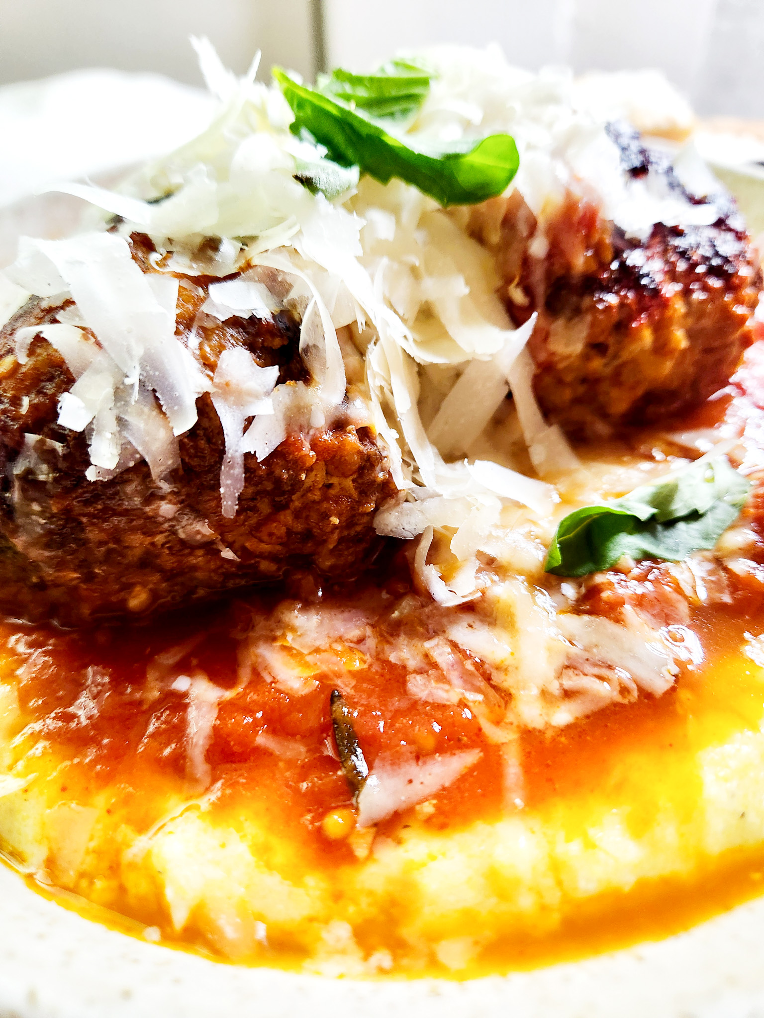 Roman Meatballs with Polenta combine ground beef, Italian sausage and prosciutto with pine nuts and fresh basil over creamy polenta.