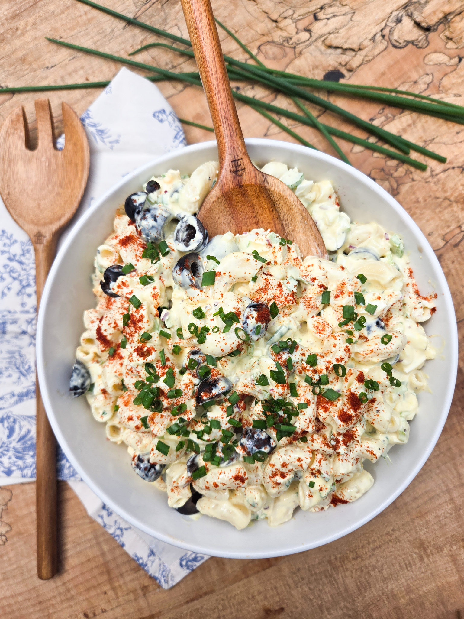 Chrissey Lou's Pasta Salad is a classic macaroni salad with creamy dressing, eggs, olives, celery, red onion and chives.